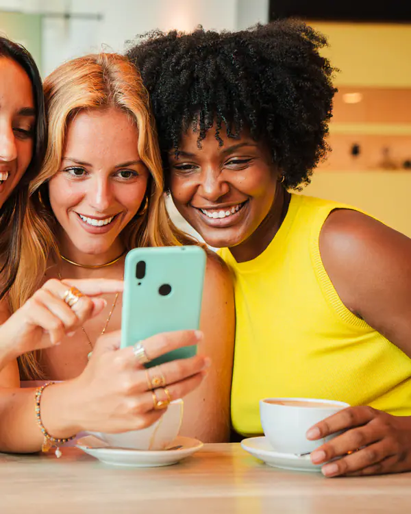 Amigas rindo juntas enquanto olham o celular