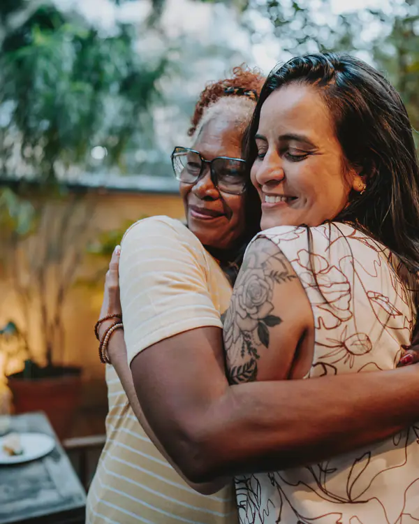 Mãe e filha se abraçando e sorrindo
